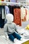 White sitting baby mannequin without face in a shop window of a children`s clothing store. Children`s casual clothing