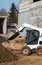 White skid steer loader at a construction site working with a soil. Industrial machinery. Industry.