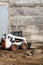 White skid steer loader at a construction site working with a soil. Industrial machinery. Industry.