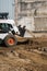 White skid steer loader at a construction site working with a soil. Industrial machinery. Industry.