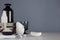 White skin care products and accessories on white wood shelf and dark grey wall, elegant bathroom decor.