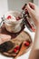 A white skin woman holding spoon of muesli in her hands with a spoonful of granola with strawberries, with nutritious