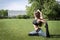 White slender girl in leggings sitting on the grass doing yoga in a clearing in the Park on a Sunny summer day