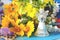 White small angel of family on a wooden blue table with a bouquet of colored field flowers