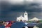 A white small chapel and people with umbrellas under a heavy rainy sky in Greece