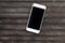 White smartphone on dark wooden table. Black screen smartphone on shabby chic background.