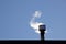 White smoke coming out of a chimney, blue sky background