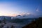 White smoke coming out of volcanoes surrounded by white clouds of mist and a clear blue sky.