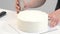 White smooth cylindrical cake blank. The confectioner creates the shape of a pastry spatula.