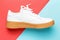 White sneaker with brown sole on red and blue background close-up.