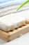 White Soap bar with foam on wooden soap dish and cotton towels on white table. Closeup