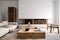 White sofa with blanket and wooden coffee table against fireplace with firewood stack. Minimalist scandinavian home interior