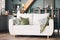 White sofa with green and grey velour cushions standing in american style modern kitchen interior