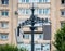 White speakers suspended from a metal pole with an old apartment building as a background. Outdoor speakers for music