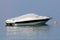 White speed boat covered with light grey tarpaulin protection anchored in local harbor next to orange buoy