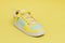 White sports sneaker with yellow inserts and laces on a yellow background. 3D render