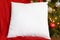 White Square PIllow Mockup Resting on Red Blanket with Lit Up Christmas Tree in Background