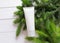 White squeeze cosmetic cream tube and green fir tree on white wooden background. Mockup moisturizer blank bottle branding,