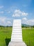 White stairs from green grass field garden up to cloud sky