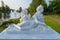 White statue of a lying woman with an angel on the shore near the lake in the park. Novi Petrivtsi, Ukraine