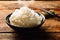 White steamed rice in round bowl on wooden table and chopsticks