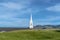 White steeple and rooftop of a church viewed from a grassy hill on a sunny day