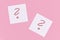 White sticky notes with handwritten question mark symbol in red ink on pink background