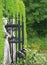 White stone sculptures at the entrance to the garden maze in Hever Castle park and black metal patterned gates on a blurred