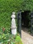 White stone sculptures at the entrance to the garden maze in Hever Castle park and black metal patterned gates on a blurred