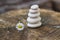 White stones cairn, poise light pebbles on wooden stump in front of green brown background, zen like, harmony and balance