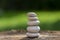 White stones cairn, poise light pebbles on wooden stump in front of green natural background, zen like, harmony and balance