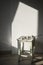 White stool with a branch of cotton flowers on wall background with a shadow from the window