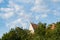 White stork pair nesting sitting on a roof of a building, from far