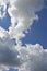 White storm clouds float across the blue sky. Beautiful atmospheric phenomenon. Natural vertical background