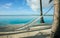 White string hammock strung between coconut palms on idyllic tropical island beach