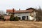 White suburban family house damaged by shrapnel during war with dilapidated facade and repaired roof