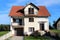 White suburban family house with wooden window blinds and garage doors surrounded with stone tiles driveway and grass