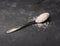 White sugar, also called table sugar in a spoon, rustic background