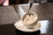 White sugar bowl with pieces of sugar and tweezers stand on a white saucer on a dark table