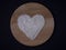 White sugar heart on a round wooden cutting board on a black background top view. Love for sweets, sweet teeth, unhealthy diet con