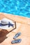 White summer hat with marine flip flops at swimming pool in summer