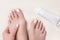 White summer pedicure. Female bare feet, toes close up and tube of cream on ivory terry towel.