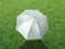 The white sun umbrella place on green grass golf course using for sun protection