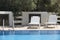 White sunbeds and swimming pool in summer