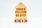 On a white surface stands a wooden model of a house with the inscription - Should you rent or buy