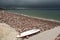 White surfboard on a rough stone shore and path to the ocean with dark storm or hurricane clouds. Stone on the beach has brown