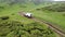 White SUV rides on a mountainous terrain on a dirt road.