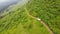 White SUV rides on a mountainous terrain on a dirt road. Aerial view.