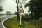 White SUV rounding corner of rural road in fog with cow warning sign in foreground - Eastern Europe