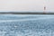 White swan in sea near pier. Jetty with modern lighthouse buoys. Beautiful seascape, copy space. Breakwater for protect ships at